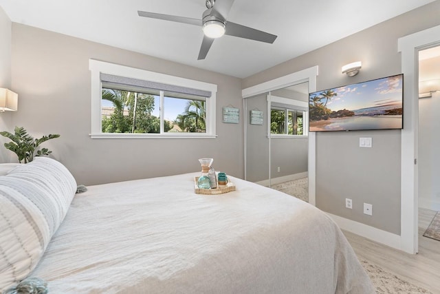 bedroom with baseboards, wood finished floors, ceiling fan, and a closet