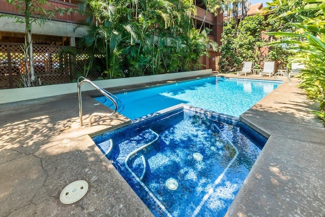 view of pool with a pool with connected hot tub