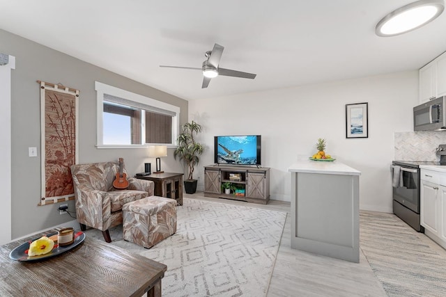living room featuring baseboards, light wood-type flooring, and ceiling fan