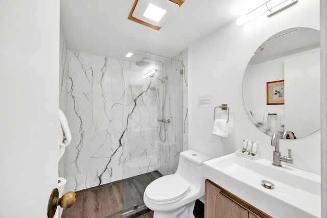 bathroom featuring toilet, tiled shower, hardwood / wood-style flooring, and vanity