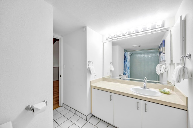 bathroom featuring walk in shower, vanity, tile patterned floors, and a textured ceiling