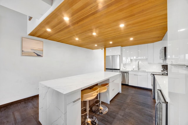 kitchen featuring tasteful backsplash, a center island, wood ceiling, stainless steel appliances, and white cabinets