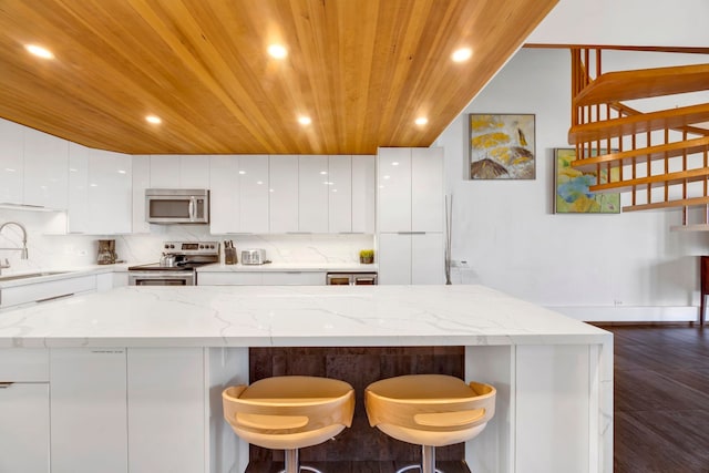 kitchen with white cabinetry, wooden ceiling, appliances with stainless steel finishes, light stone countertops, and sink