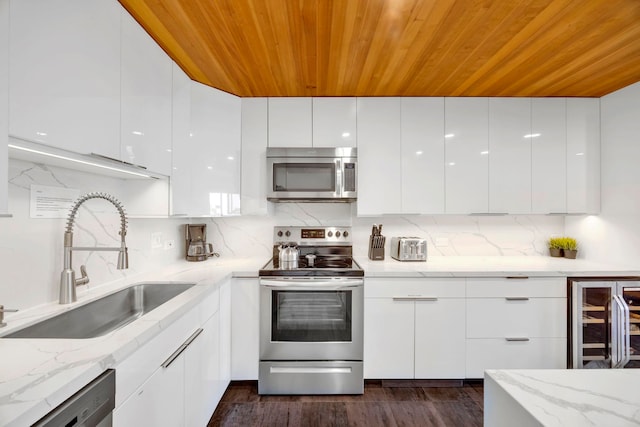 kitchen featuring white cabinetry, wooden ceiling, appliances with stainless steel finishes, light stone counters, and sink