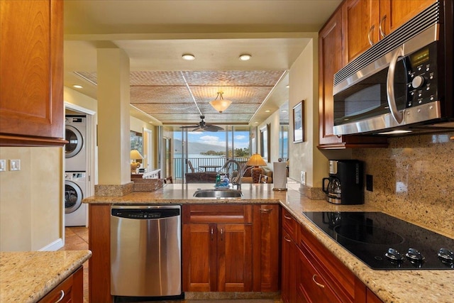 kitchen featuring sink, stainless steel appliances, tasteful backsplash, kitchen peninsula, and stacked washer and clothes dryer