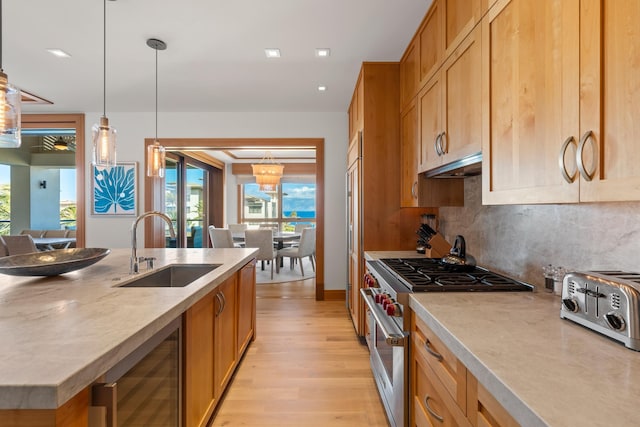 kitchen featuring wine cooler, decorative light fixtures, light countertops, a sink, and high end stove