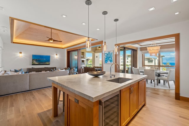 kitchen with wine cooler, open floor plan, light countertops, an island with sink, and a raised ceiling