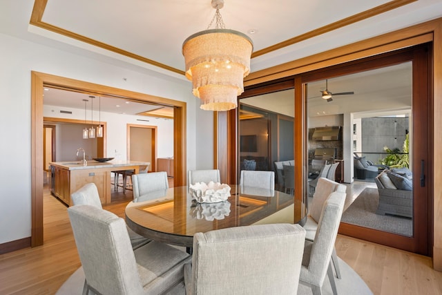 dining space with crown molding, light wood-style flooring, baseboards, and ceiling fan with notable chandelier