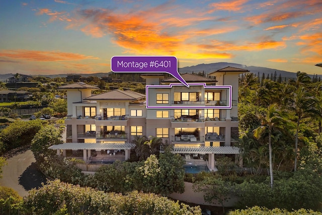 back of house at dusk with a mountain view and a pergola