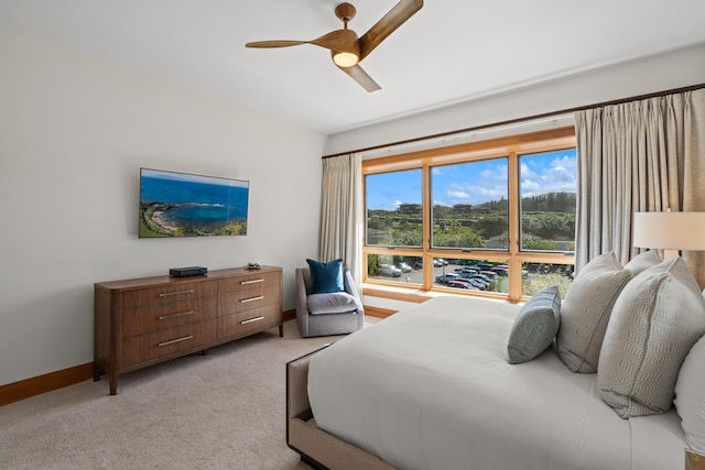 bedroom with light carpet, ceiling fan, and baseboards