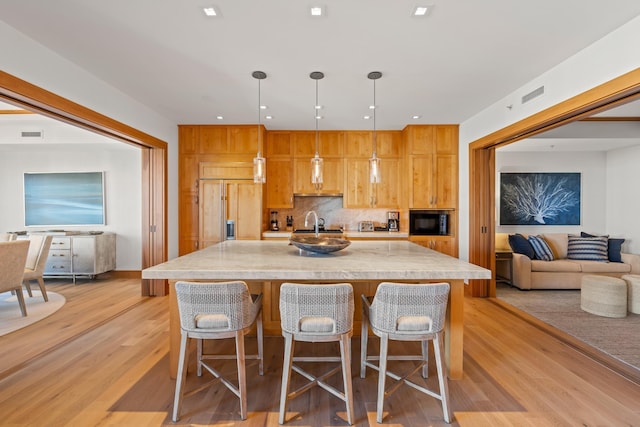 kitchen featuring pendant lighting, light countertops, visible vents, open floor plan, and built in appliances