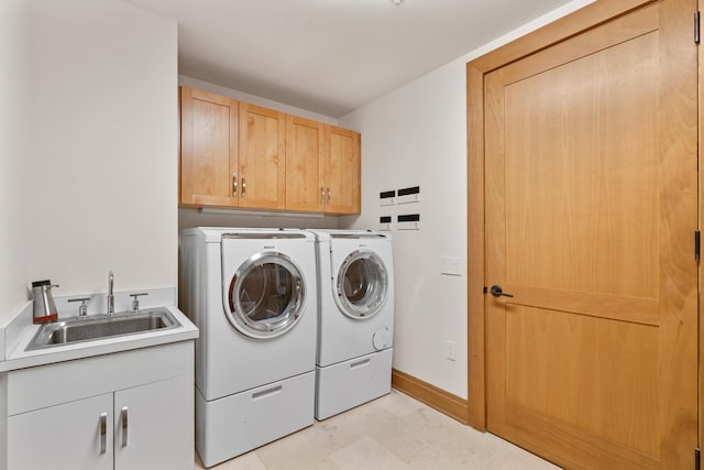 washroom featuring cabinet space, a sink, baseboards, and separate washer and dryer