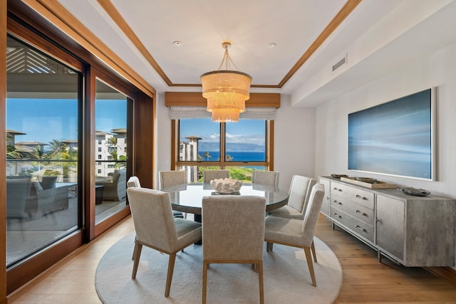 dining area featuring ornamental molding, light wood-type flooring, visible vents, and a notable chandelier