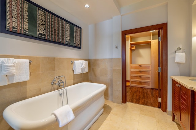 3800 Wailea Alanui Dr Unit B-102, Kihei, HI 96753 - bathroom with tile walls, a freestanding tub, vanity, recessed lighting, and a wainscoted wall