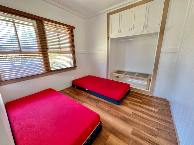 bedroom with ornamental molding, light hardwood / wood-style floors, and a closet