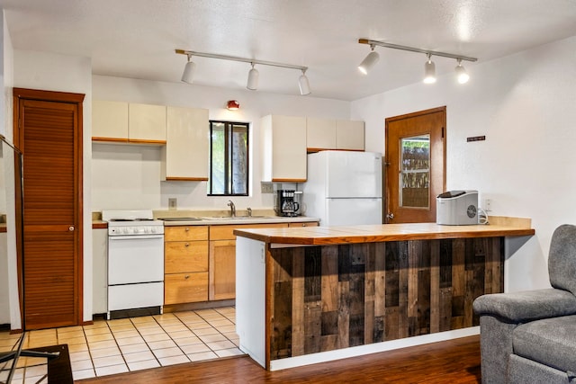 kitchen featuring kitchen peninsula, sink, light hardwood / wood-style flooring, range, and white fridge