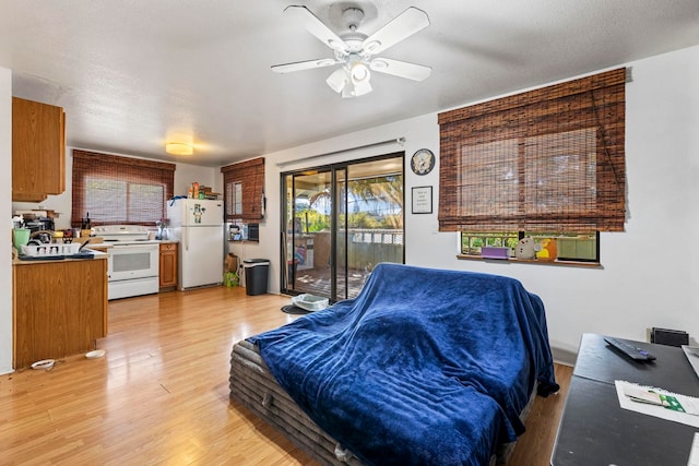 bedroom featuring access to outside, white refrigerator, light hardwood / wood-style flooring, ceiling fan, and a textured ceiling