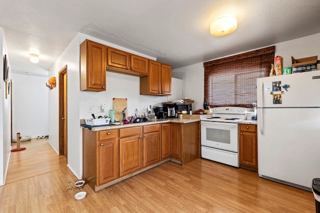 kitchen featuring a textured ceiling, white appliances, and light wood-type flooring