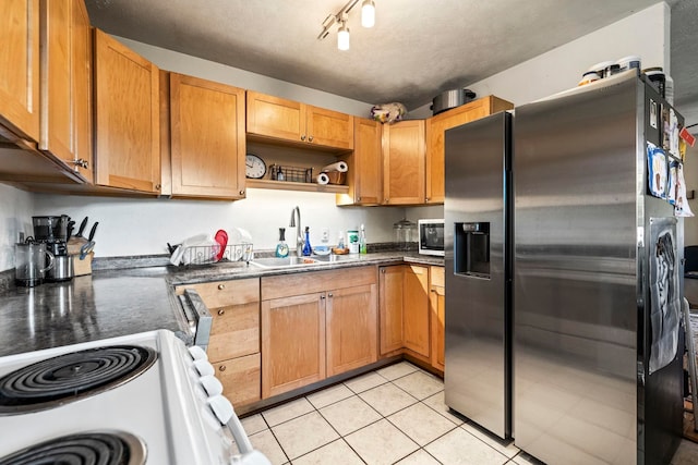 kitchen with rail lighting, sink, light tile patterned floors, and stainless steel appliances