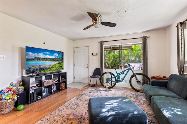 living room featuring ceiling fan, a textured ceiling, and hardwood / wood-style flooring