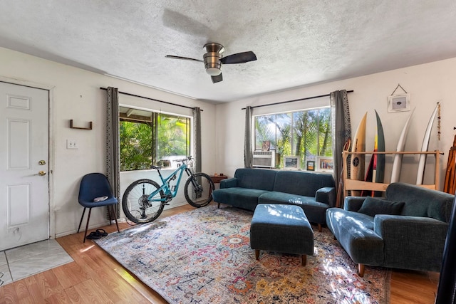 living room with ceiling fan, wood-type flooring, and a textured ceiling