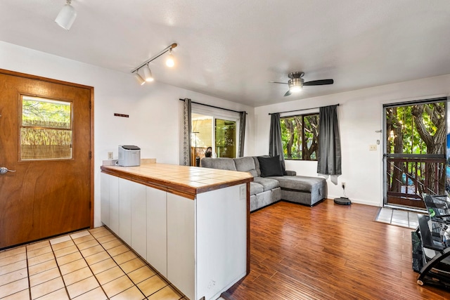 kitchen featuring ceiling fan, tile counters, kitchen peninsula, light hardwood / wood-style floors, and white cabinets