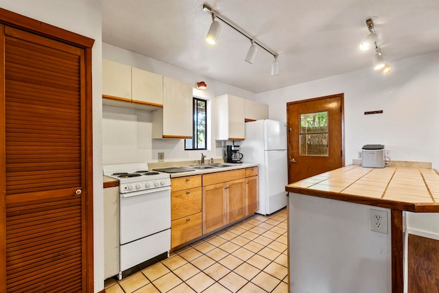 kitchen featuring kitchen peninsula, white appliances, sink, light tile patterned floors, and tile counters