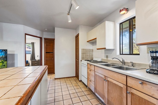 kitchen with tile countertops, track lighting, sink, light tile patterned flooring, and white range with gas stovetop