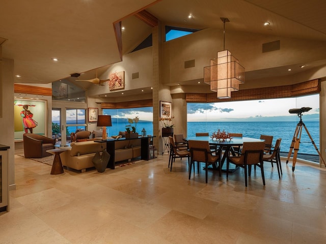 dining space with a water view, high vaulted ceiling, and a notable chandelier