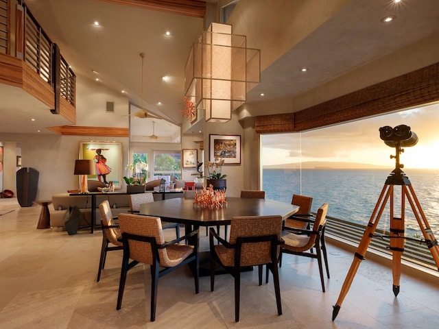 dining space featuring a towering ceiling and a water view