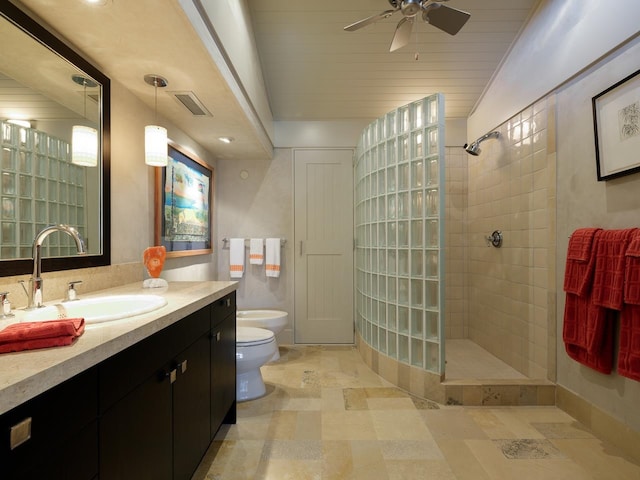 bathroom featuring a tile shower, vanity, ceiling fan, a bidet, and toilet