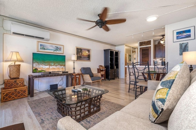 living room featuring a textured ceiling, light hardwood / wood-style flooring, and a wall mounted air conditioner