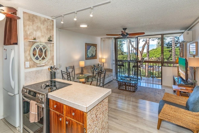 kitchen featuring stainless steel electric stove, light hardwood / wood-style floors, a textured ceiling, white fridge, and a wall unit AC