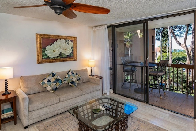 living room with ceiling fan, light hardwood / wood-style floors, a textured ceiling, and a wall of windows