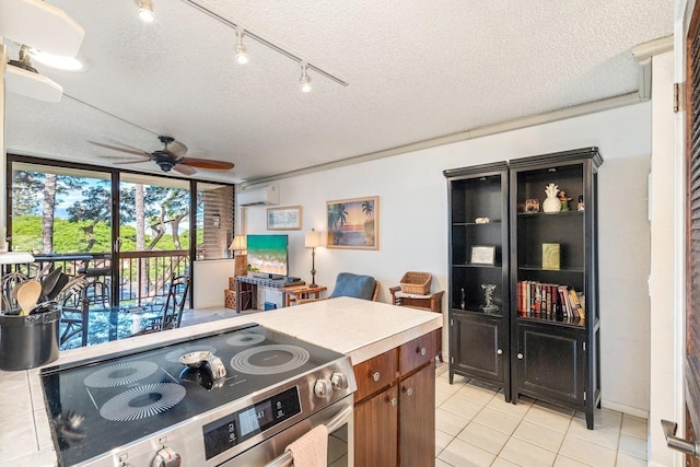 kitchen featuring ceiling fan, light tile patterned flooring, electric stove, and a textured ceiling