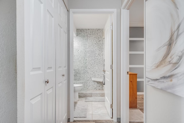 bathroom featuring tiled shower and toilet