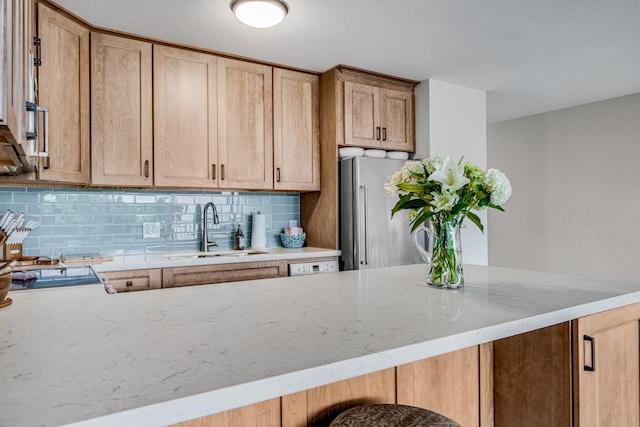 kitchen featuring kitchen peninsula, sink, light stone counters, and backsplash