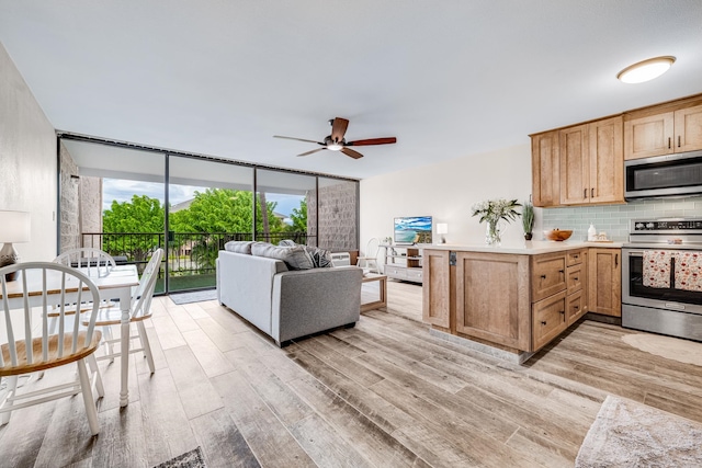 kitchen featuring appliances with stainless steel finishes, kitchen peninsula, light hardwood / wood-style floors, ceiling fan, and decorative backsplash