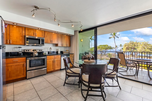 2653 S Kihei Rd Unit 306, Kihei, HI 96753 - kitchen with appliances with stainless steel finishes, brown cabinetry, dark countertops, and light tile patterned floors
