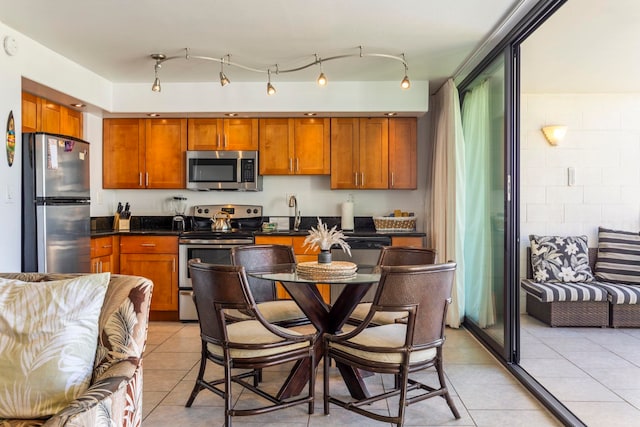 2653 S Kihei Rd Unit 306, Kihei, HI 96753 - kitchen featuring appliances with stainless steel finishes, light tile patterned floors, dark countertops, brown cabinets, and a sink