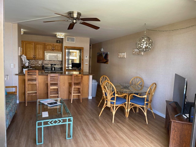 dining space featuring ceiling fan with notable chandelier, wood-type flooring, and sink