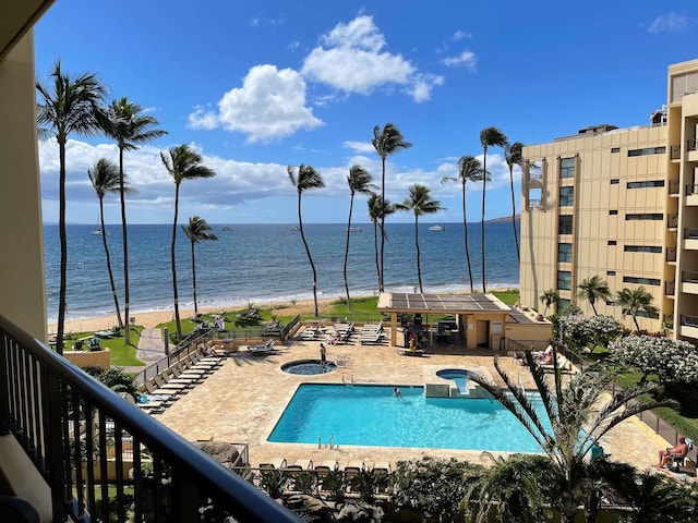 view of pool with a patio area, a view of the beach, a water view, and a hot tub