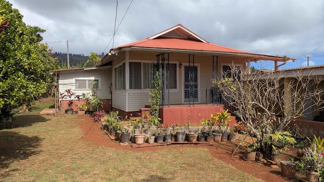 view of front of home with metal roof, a porch, and a front yard