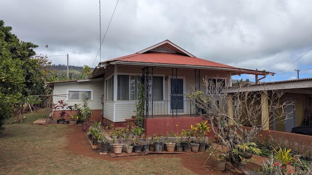 view of front of property featuring metal roof, covered porch, and a vegetable garden