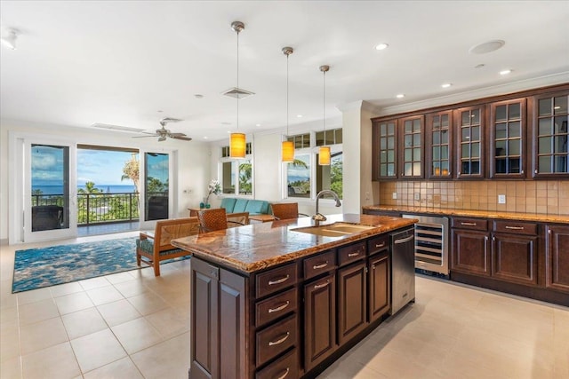 kitchen with an island with sink, a sink, decorative light fixtures, tasteful backsplash, and wine cooler