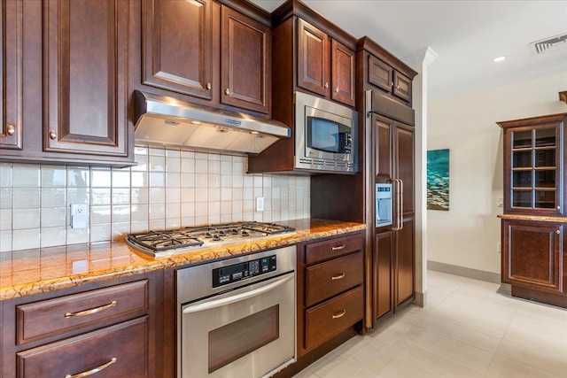 kitchen with light stone counters, built in appliances, decorative backsplash, dark brown cabinetry, and light tile patterned flooring