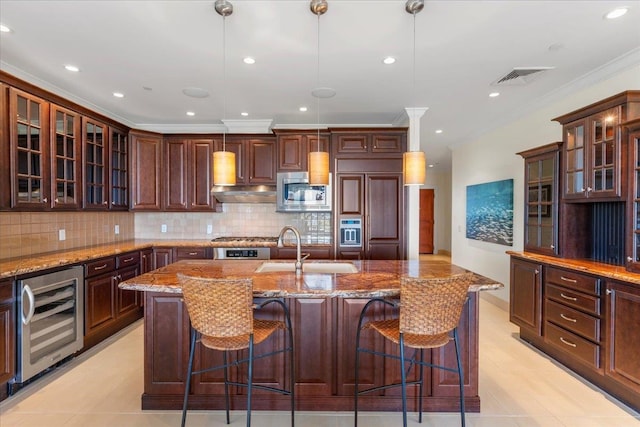 kitchen featuring sink, tasteful backsplash, a kitchen island with sink, pendant lighting, and wine cooler