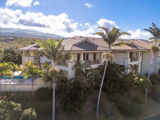 view of front of house with stucco siding, a balcony, a mountain view, and a tiled roof