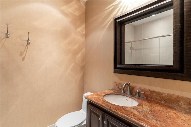 bathroom with walk in shower, vanity, and toilet