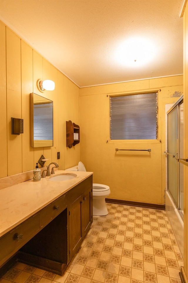 full bathroom with enclosed tub / shower combo, vanity, and toilet